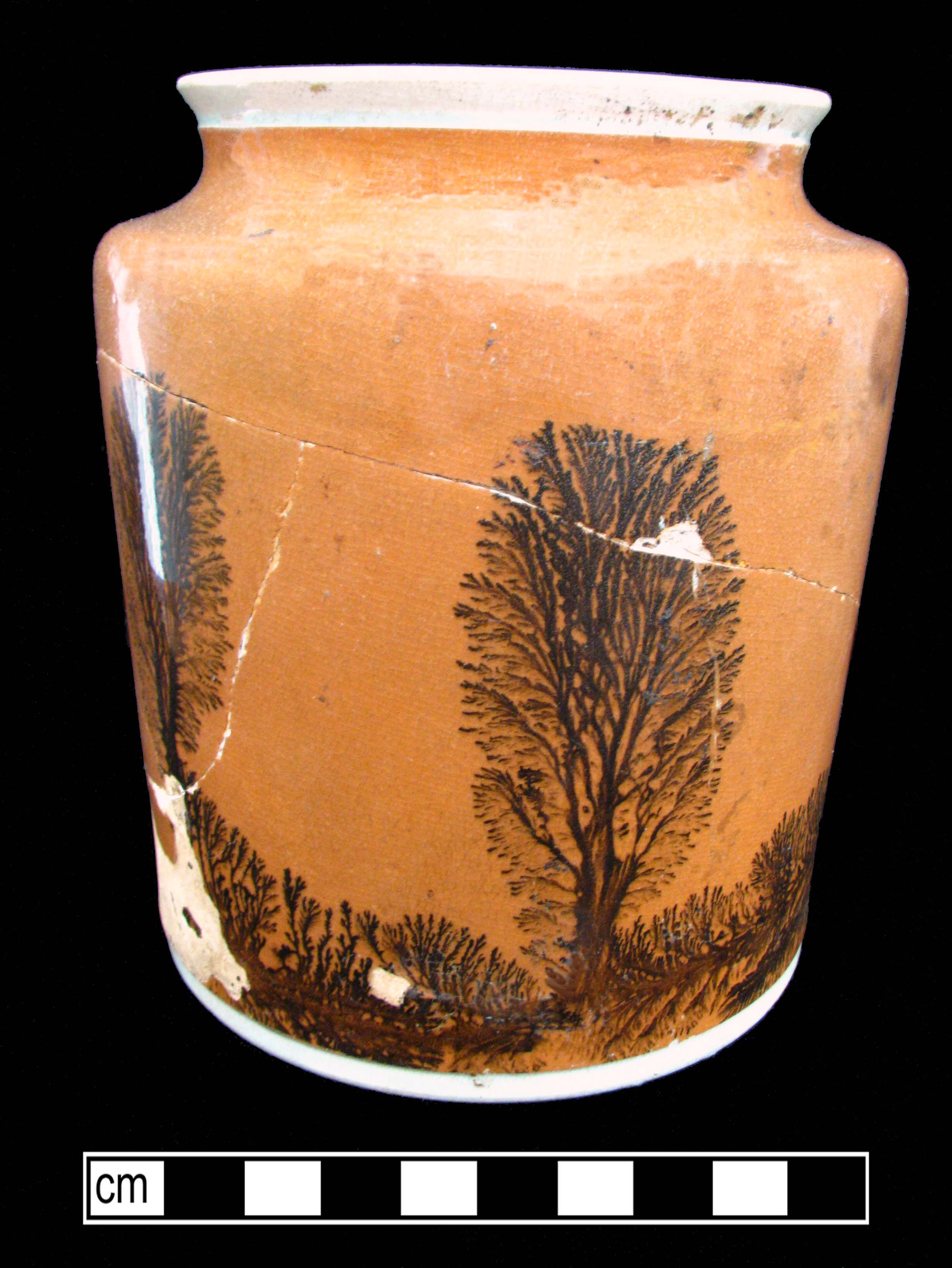 Orange straight sided, large mouthed ceramic vessel with a black fernlike design on the base and sides.